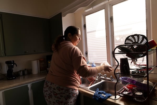 Arelis Ayala washes dishes while making breakfast for her family on Sunday, March 23, 2025, in Rochester, N.Y. (Toni Duncan via AP)