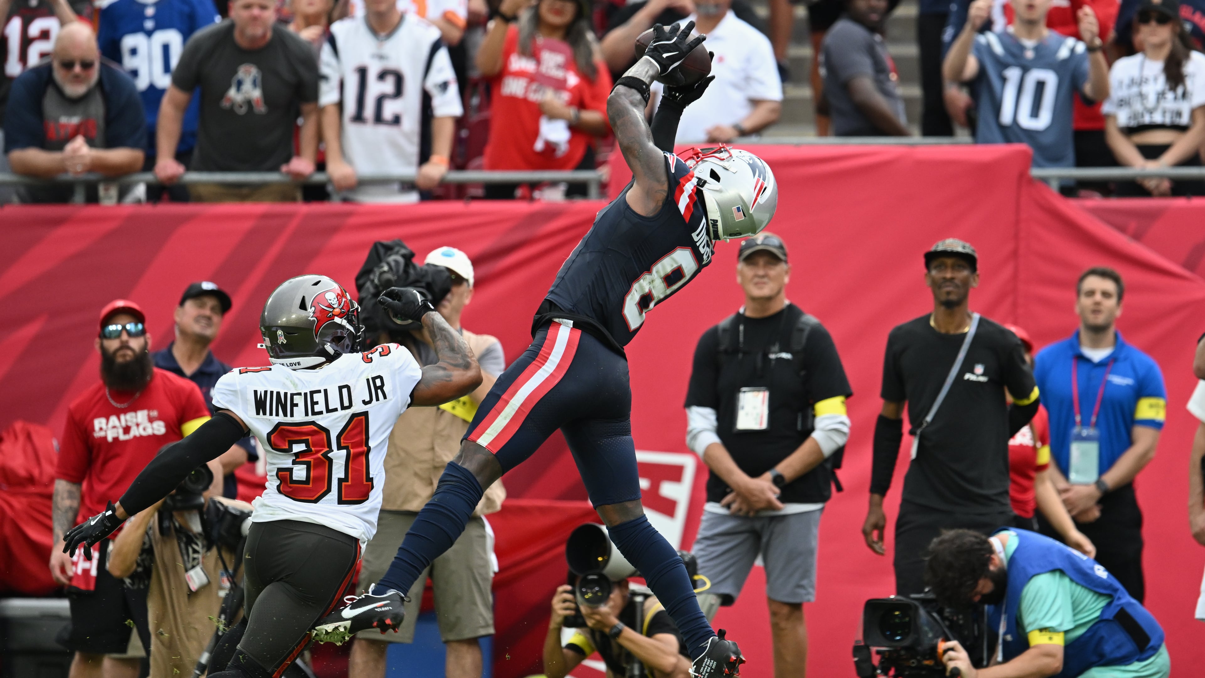 New England Patriots wide receiver Stefon Diggs (8) catches a pass for a touchdown against Tampa Bay Buccaneers safety Antoine Winfield Jr. (31) during the first half of an NFL football game Sunday, Nov. 9, 2025, in Tampa, Fla. (AP Photo/Jason Behnken)