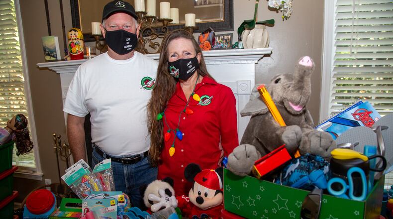 Portrait of Michael and Marika Chasse with some of the items for shoeboxes currently filling their Johns Creek home. For the past six years, the Chasses have hosted a packing party for Operation Christmas Child shoeboxes, a project of Samaritan's Purse. Friends and neighbors will help pack 1,000 shoeboxes. PHIL SKINNER FOR THE ATLANTA JOURNAL-CONSTITUTION.
