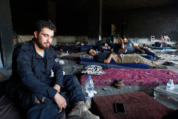Syrian security forces rest inside a burned out shop as they deploy in Mazraa village on the outskirts of Sweida city, in southern Syria, Sunday, July 20, 2025. (AP Photo/Omar Sanadiki)