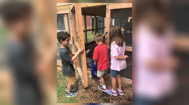 Lovin Elementary student Aiden Williams opens the door to the school's walk-in chicken coop for siblings Katherine and Adrian Deventure. (Photo contributed)