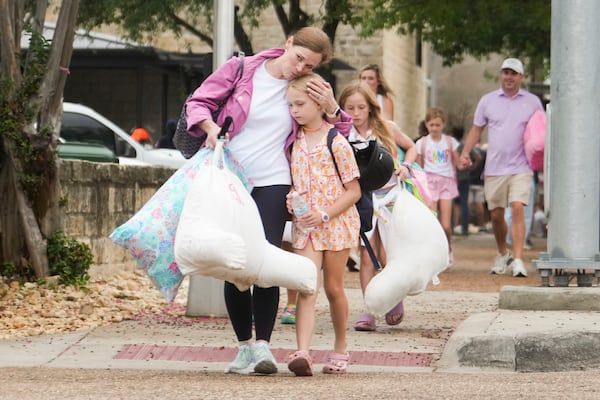A woman and a child embrace after girls from Camp Waldemar, near the North fork of the Guadalupe River, are reunited with their families after heavy rainfall in Central Texas, Saturday, July 5, 2025. (Jason Fochtman/Houston Chronicle via AP)