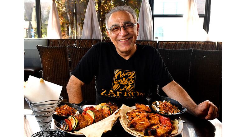 Peter Teimori, chef and owner of Zafron Restaurant in Sandy Springs, poses for a portrait with his (from left) bread, Kashk Bademjoon (eggplant spread with crispy mint and fried onions), Beef Shish Kebabs with grilled vegetables, Zafron Wings with grilled tomatoes, and a second serving of Kashk Bademjoon. (Styling by Peter Teimori / Chris Hunt for the AJC)