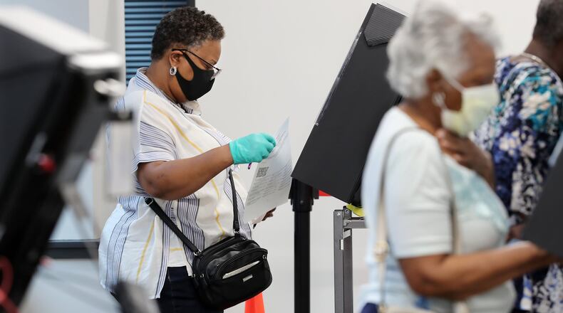 A voter wears a mask and gloves to cast her vote at stations at least six feet apart on the first day of early voting at the Cobb County Board of Elections & Registration on Monday, May 18, 2020, in Marietta. CURTIS COMPTON / CCOMPTON@AJC.COM
