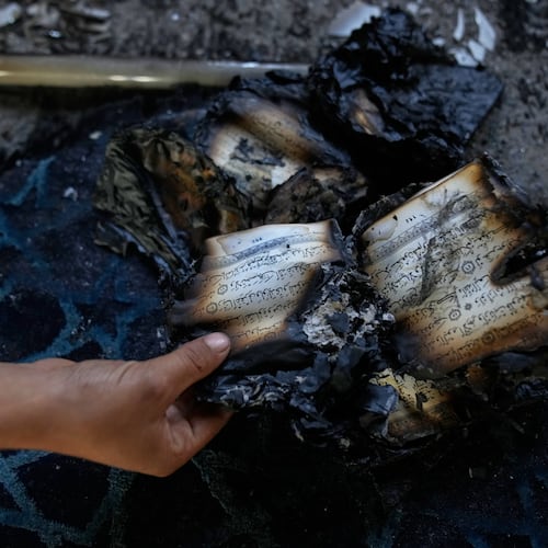 A boy inspects burnt copies of Quran inside a mosque that was torched and defaced by Israeli settlers overnight, in the West Bank town of Deir Istiya Thursday, Nov. 13, 2025. (AP Photo/Nasser Nasser)