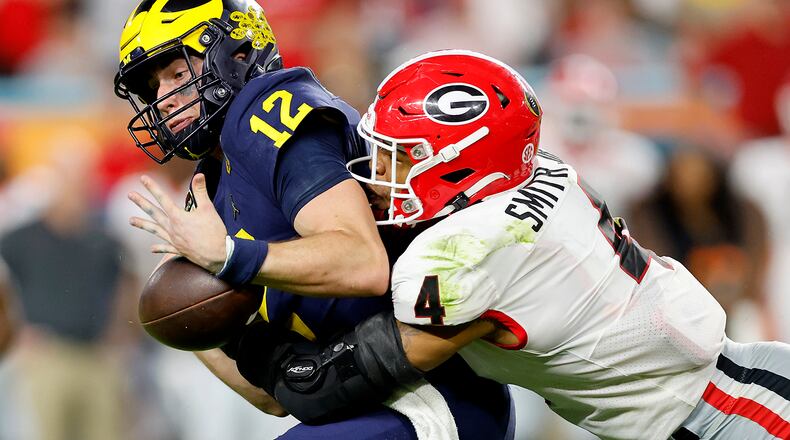 Nolan Smith #4 of the Georgia Bulldogs forces a fumble by Cade McNamara #12 of the Michigan Wolverines in the fourth quarter in the Capital One Orange Bowl for the College Football Playoff semifinal game at Hard Rock Stadium on Dec. 31, 2021, in Miami Gardens, Florida. (Michael Reaves/Getty Images/TNS)
