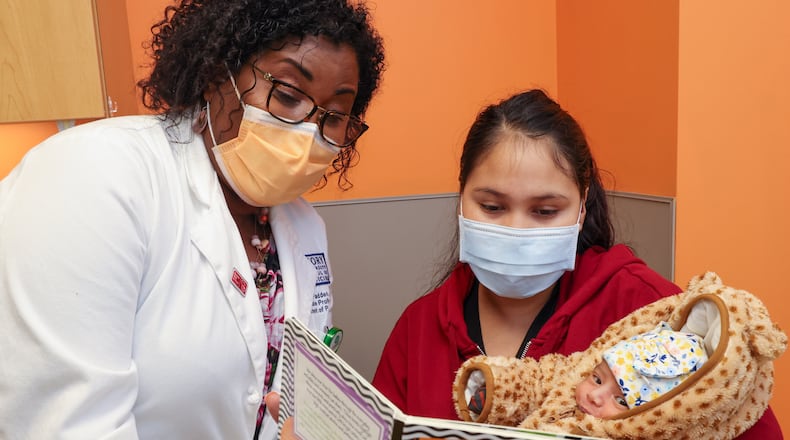 Pediatrician Dr. Terri McFadden encourages Maria Del Rosario to read to her baby, Camila Reyes Espinoza, during a visit to Children's Healthcare of Atlanta at Hughes Spalding. PHIL SKINNER FOR THE ATLANTA JOURNAL-CONSTITUTION