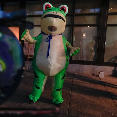 A person paints a portrait of a demonstrator dressed in an inflatable costume outside a United States Immigration and Customs Enforcement (ICE) facility on Tuesday, Oct. 21, 2025, in Portland, Ore. (AP Photo/Jenny Kane)