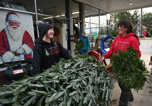 Rachel Quiggins (left) and Michelle Stell share a smile as they help customers at Tradition Trees’ Chamblee lot location. A Powerball winner could pick up the tree tab for the entire city. (Hyosub Shin/AJC)