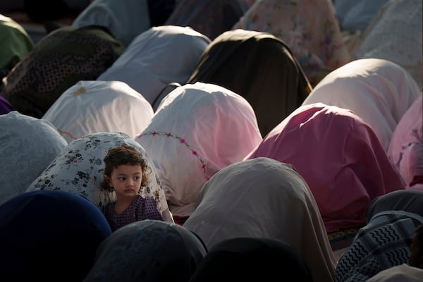A child looks on as people pray at National Mosque for the Eid al-Fitr, marking the end the holy fasting month of Ramadan in Kuala Lumpur, Malaysia, Monday, March 31, 2025. (AP Photo/Vincent Thian)