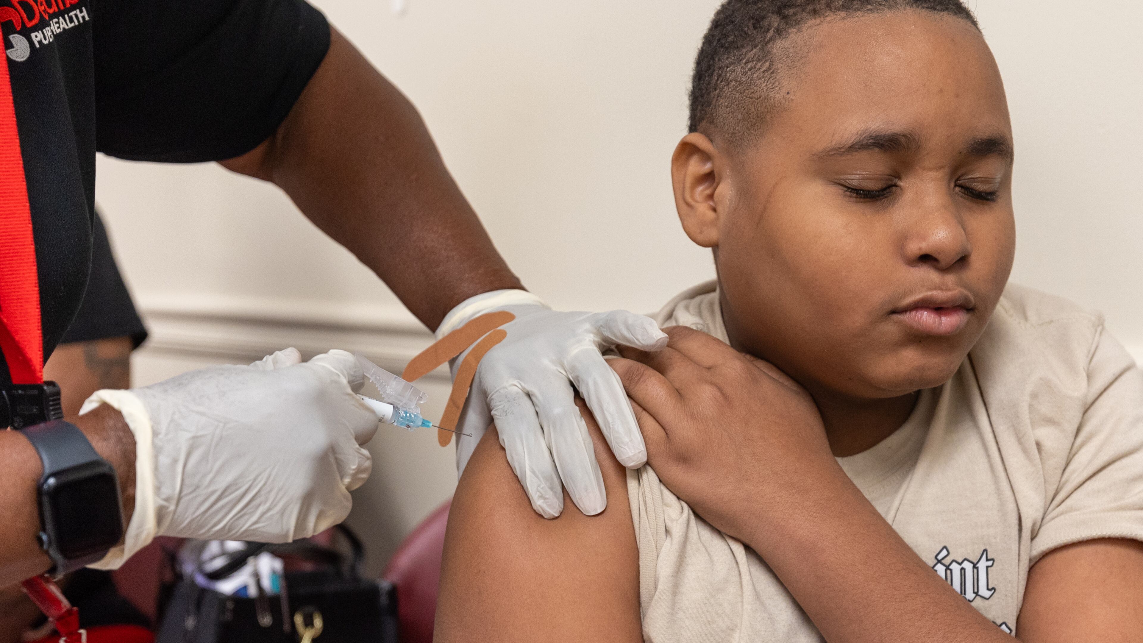 King Taylor, 13, gets a back-to-school vaccine shot at Clifton Springs Health Center in Decatur on Tuesday, July 22, 2025. DeKalb's health centers have extended their hours on certain days so that families can get the vaccines they need before school starts. (Arvin Temkar/AJC)