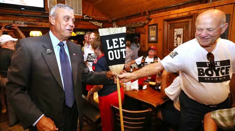 Supporter Howard Wolf hands Mike Boyce a broom as he arrives greeting the crowd at his watch party at Williams Brothers BBQ in the Cobb County commission chairman's race last month. Curtis Compton, ccompton@ajc.com