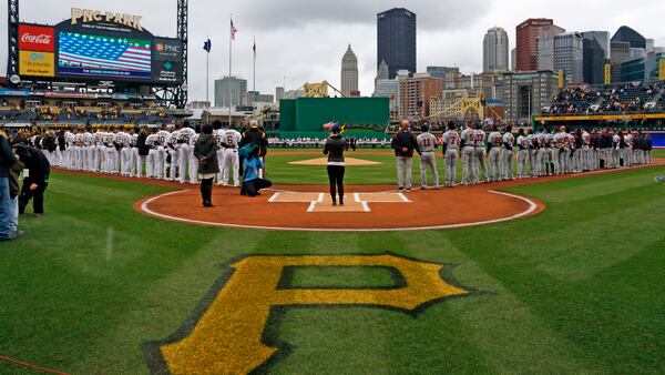 The Pittsburgh Pirates line the third baseline and the Atlanta Braves line the first baseline for the National Anthem before the Pirates' home opener Friday, April 7, 2017, at PNC Park in Pittsburgh.
