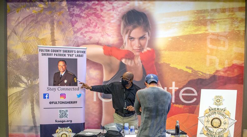 Tommy White talks to a potential recruit at the Fulton County Sheriff's Office job fair at LA fitness in Atlanta Friday, Feb. 11, 2022.   STEVE SCHAEFER FOR THE ATLANTA JOURNAL-CONSTITUTION