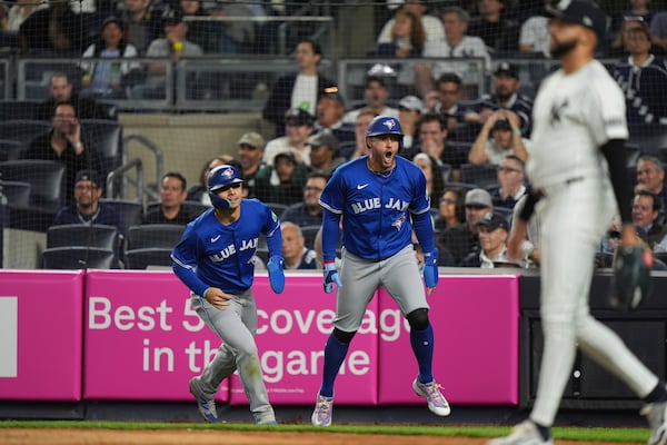 Toronto Blue Jays' Addison Barger, center, and Andrés Giménez, left, celebrate as New York Yankees pitcher Devin Williams, right, walks back to the pitchers mound after they scored on a two-run double by Alejandro Kirk during the ninth inning of a baseball game Friday, April 25, 2025, in New York. (AP Photo/Frank Franklin II)