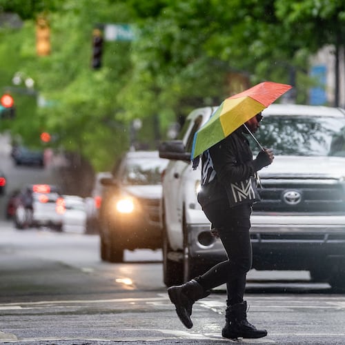 A person with an umbrella crosses Peachtree Street in downtown Atlanta. Isolated rain showers are projected to pop up across the area beginning around 2 p.m. Tuesday and develop into widespread storms closer to nightfall. (Ben Hendren for the AJC)