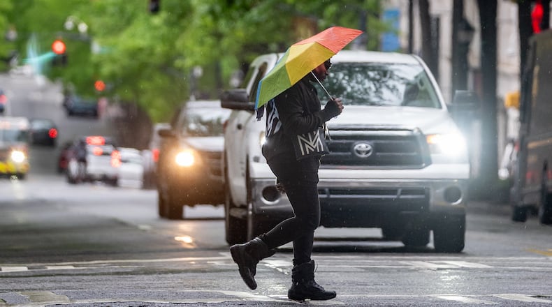A person with an umbrella crosses Peachtree Street in downtown Atlanta on Monday. (Ben Hendren for the AJC)