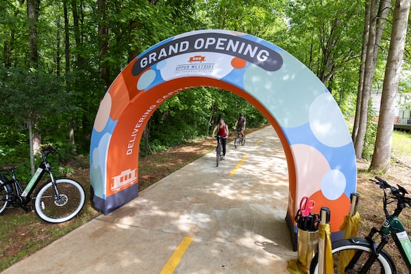 Anastasia and Alex Grizel bike through a grand opening display at the Woodall Rail Trail in Atlanta on May 9, 2025. It’s the first completed segment of the Silver Comet connector in the city of Atlanta. (Arvin Temkar/AJC)
