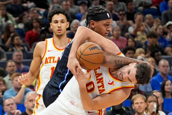 Orlando Magic forward Paolo Banchero, center, and Atlanta Hawks forward Georges Niang, right, battle for a deflected shot during the second half of an NBA basketball game, Tuesday, April 8, 2025, in Orlando, Fla. (AP Photo/John Raoux)