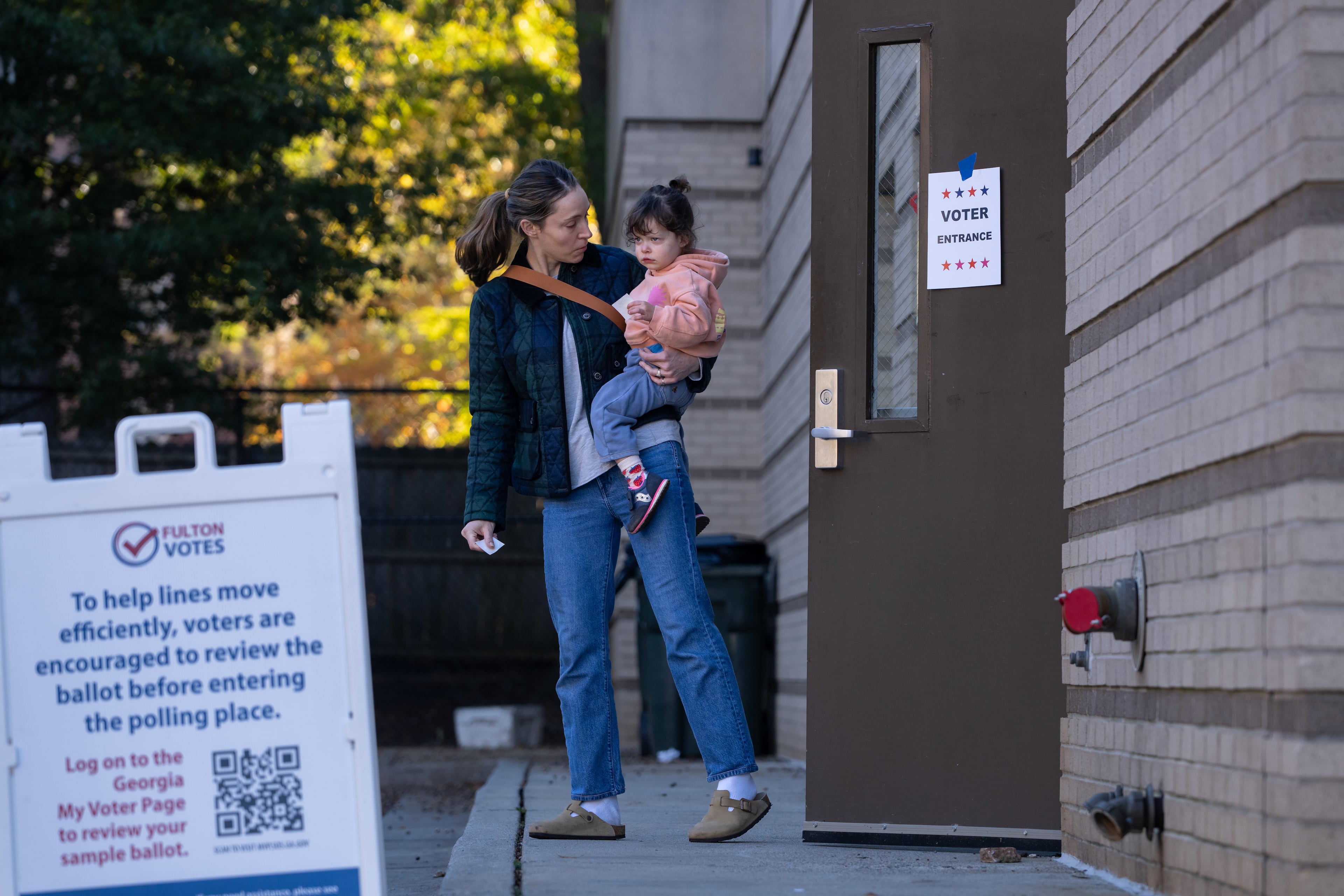 A mother and daughter leave the voting precinct at the Joan P. Garner Library at Ponce De Leon Avenue NE in Atlanta holding "I'm a Georgia voter" stickers on Monday, November 4, 2025 (Ben Hendren for the AJC)