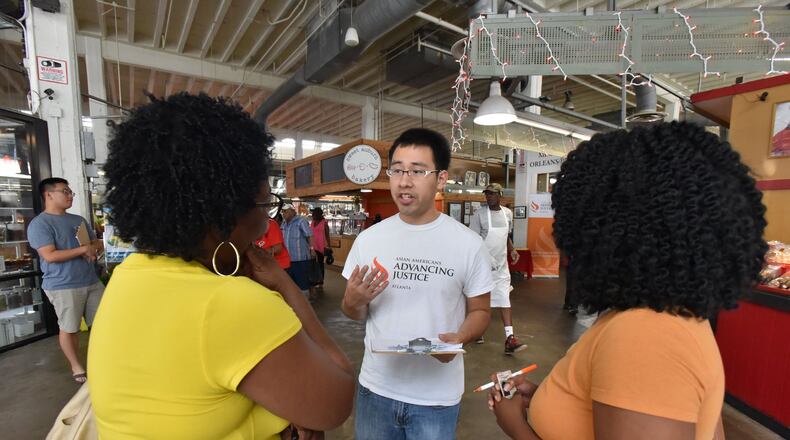Norman Cervantes (center), with Asian Americans Advancing Justice - Atlanta, talks to Bernita Holsey (left) of Atlanta as he helps Holsey’s granddaughter Dariah Holsey (right), 19, with her voter registration in The Sweet Auburn Curb Market on Saturday, August 20, 2016. HYOSUB SHIN / HSHIN@AJC.COM