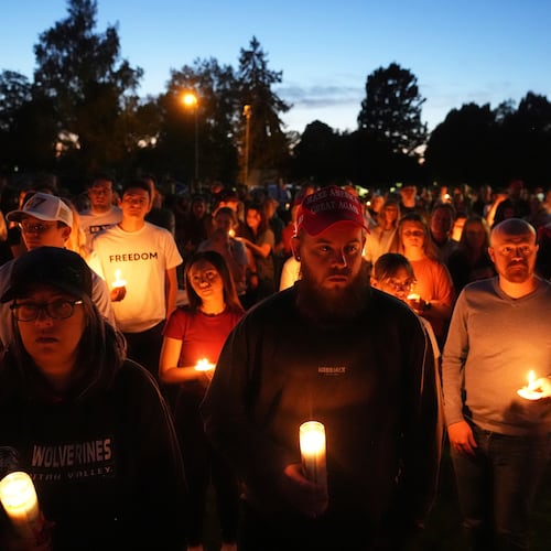 FILE - Carly Jenkins, left, and Alex Thomson, center, pay their respects alongside others during a vigil for Charlie Kirk on Sept. 12, 2025, in Provo, Utah. (AP Photo/Lindsey Wasson, File)