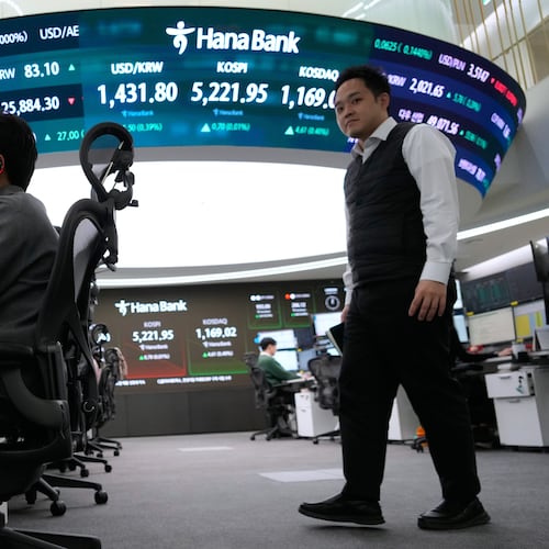 A currency trader talks on the phone near a screen showing the Korea Composite Stock Price Index (KOSPI), top center, and the foreign exchange rate between U.S. dollar and South Korean won, top center left, at the foreign exchange dealing room of the Hana Bank headquarters in Seoul, South Korea, Friday, Jan. 30, 2026. (AP Photo/Ahn Young-joon)