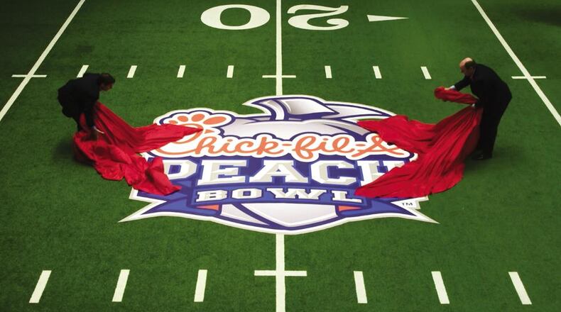 College Football Hall of Fame CEO Dennis Adamovich (left) and Peach Bowl Inc. CEO Gary Stokan unveil a Chick-fil-A Peach Bowl logo on the Hall of Fame’s indoor playing field.
