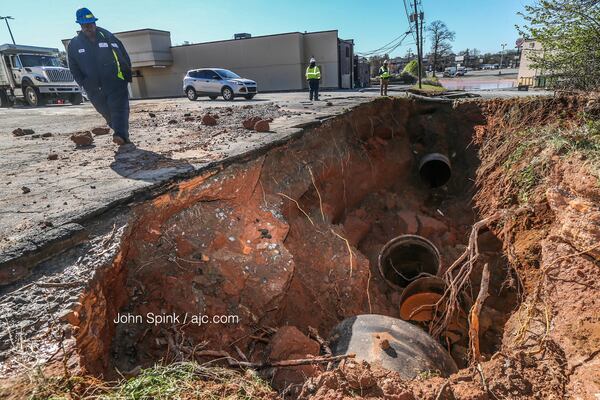 Officials check out a sinkhole after a water main break in Doraville. JOHN SPINK / JSPINK@AJC.COM