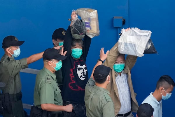 FILE - Pro-democracy activists Leung Kwok-hung, known as "Long Hair," left, and Lee Cheuk-yan raise their hands as they are escorted by Correctional Services officers to a prison van for a court in Hong Kong, on May 28, 2021. (AP Photo/Kin Cheung, File)