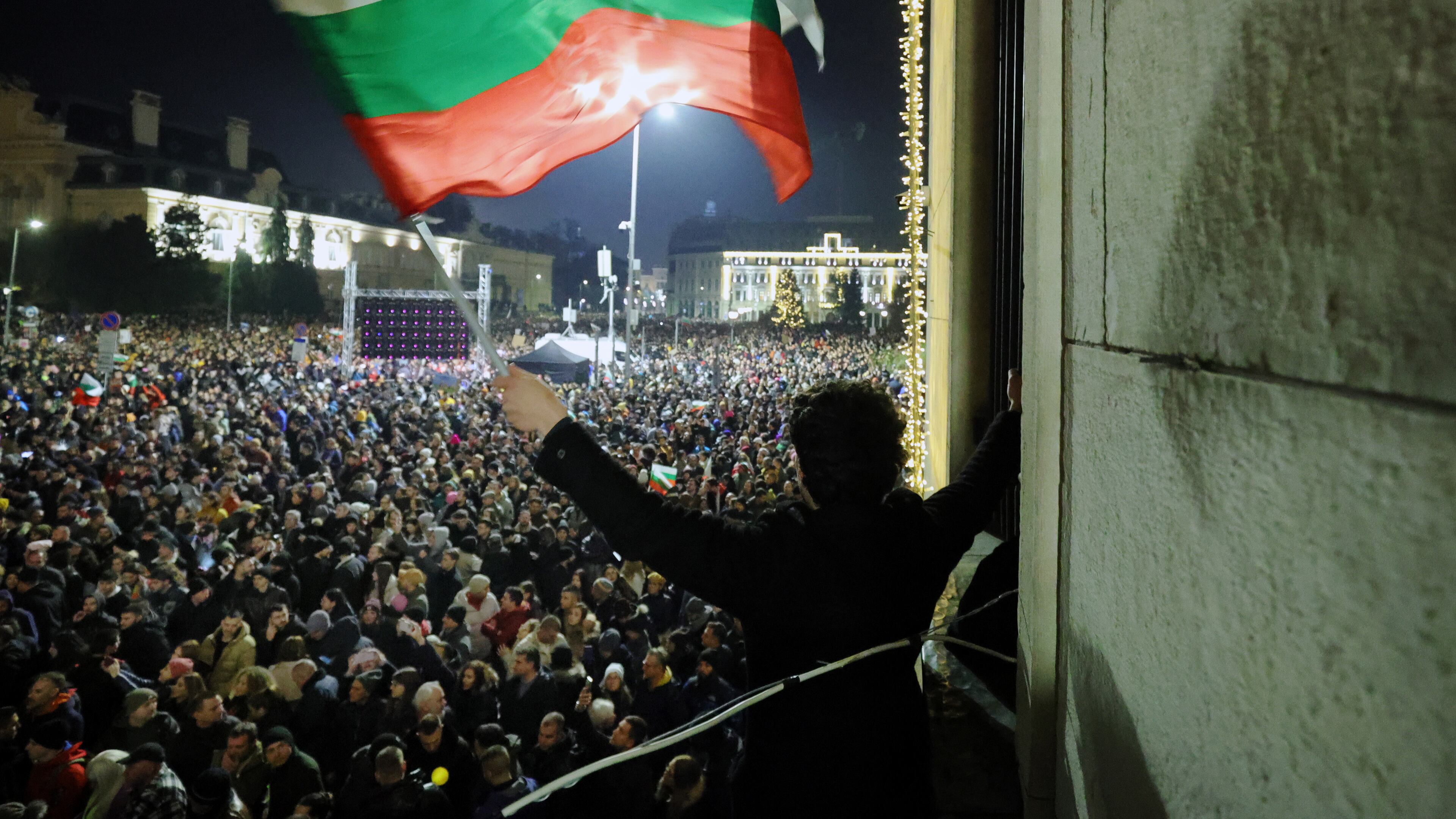 A student waves a Bulgarian flag as a swelling crowd of tens of thousands of Bulgarians filled Sofia's central square, demanding the government's resignation amid rising anger over corruption and contested economic policies, Sofia, Bulgaria, Wednesday, Dec. 10, 2025. (AP Photo/Valentina Petrova)