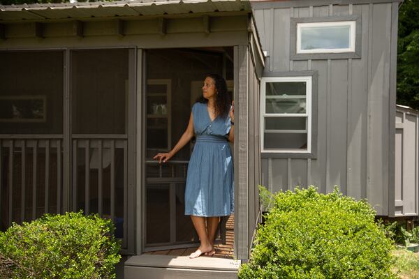 Cabbagetown resident Nadia Giordani stands in the door of her 300-square-foot tiny home in her backyard that she uses as a short-term rental to help her pay for rising property taxes in the area. (Riley Bunch/AJC)