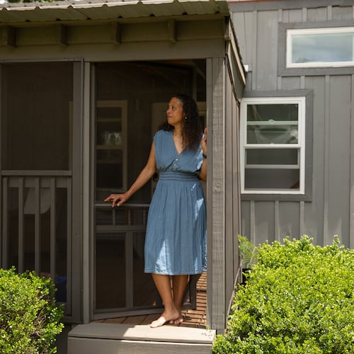 Cabbagetown resident Nadia Giordani stands in the door of her 300-square-foot tiny home in her backyard that she uses as a short-term rental to help her pay for rising property taxes in the area. (Riley Bunch/AJC)