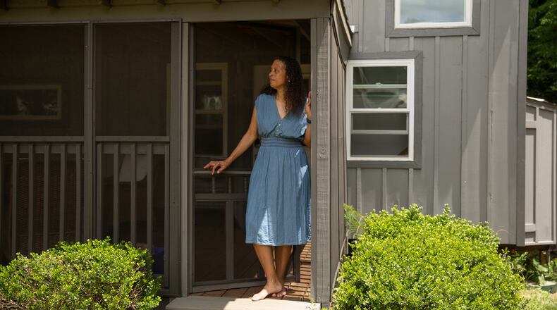 Cabbagetown resident Nadia Giordani stands in the door of her 300-square-foot tiny home in her backyard that she uses as a short-term rental to help her pay for rising property taxes in the area. (Riley Bunch/AJC)