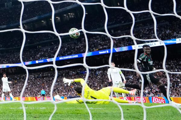 Arsenal's Bukayo Saka, right, scores the opening goal during the Champions League quarterfinals second leg soccer match between Real Madrid and Arsenal at the Santiago Bernabeu stadium in Madrid, Wednesday, April 16, 2025. (AP Photo/Manu Fernandez)