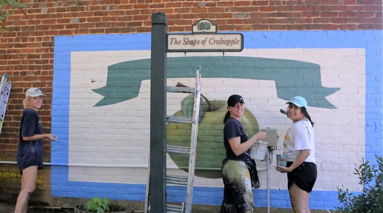 (Right to left) Gabrielle Poteet, Katie Eidson (the project manager) and Alondra Arevalo restored two murals in downtown Milton over the weekend of Aug. 13, 2021. (Photo taken by Robert Meyers of the Milton Historical Society and courtesy of Milton's Facebook page)
