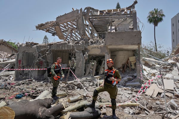 Israeli soldiers inspect the site struck by a direct missile strike launched from Iran in Tel Aviv, Israel, on Sunday, June 22, 2025. (AP Photo/Bernat Armangue)