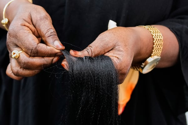A braider separates pieces of synthetic braiding hair to prepare for a client at Eve's African Braiding in College Park, Ga., Tuesday, May 6, 2025. (AP Photo/Stephanie Scarbrough)