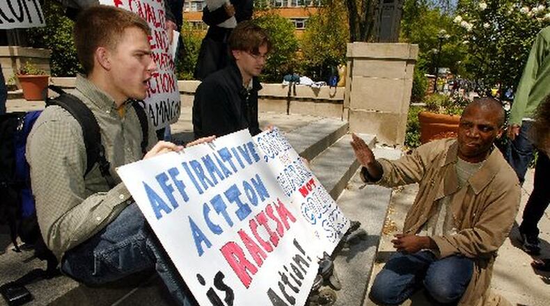 Affirmative action proponent the Rev. Valdiveso Matthews (right), from the Eglise Gnostique church, argues with University of Michigan student James Justin Wilson (left), holding a sign stating “Affirmative Action is Racism in Action” on the steps of the Michigan Union on the University of Michigan campus on May 14, 2002, in Ann Arbor, Mich. Jared Suess sits next to Wilson and holds a sign stating “Content of Character not color of skin.” The U.S. Supreme Court ruled on cases involving the University of Michigan’s undergraduate admissions and its law school in 2003. AP FILE PHOTO / DANNY MOLOSHOK