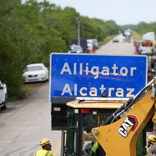FILE - A loader holds a sign reading "Alligator Alcatraz" in its bucket as workers install it at the entrance to a new migrant detention facility at Dade-Collier Training and Transition facility, July 3, 2025, in Ochopee, Fla. (AP Photo/Rebecca Blackwell)