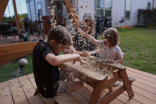 Eileen Lamb, center, who was diagnosed with autism as an adult, works with her son Charlie Lamb, left, who also has autism, and daughter Billie at their home, Monday, May 12, 2025, in Austin, Texas. (AP Photo/Eric Gay)