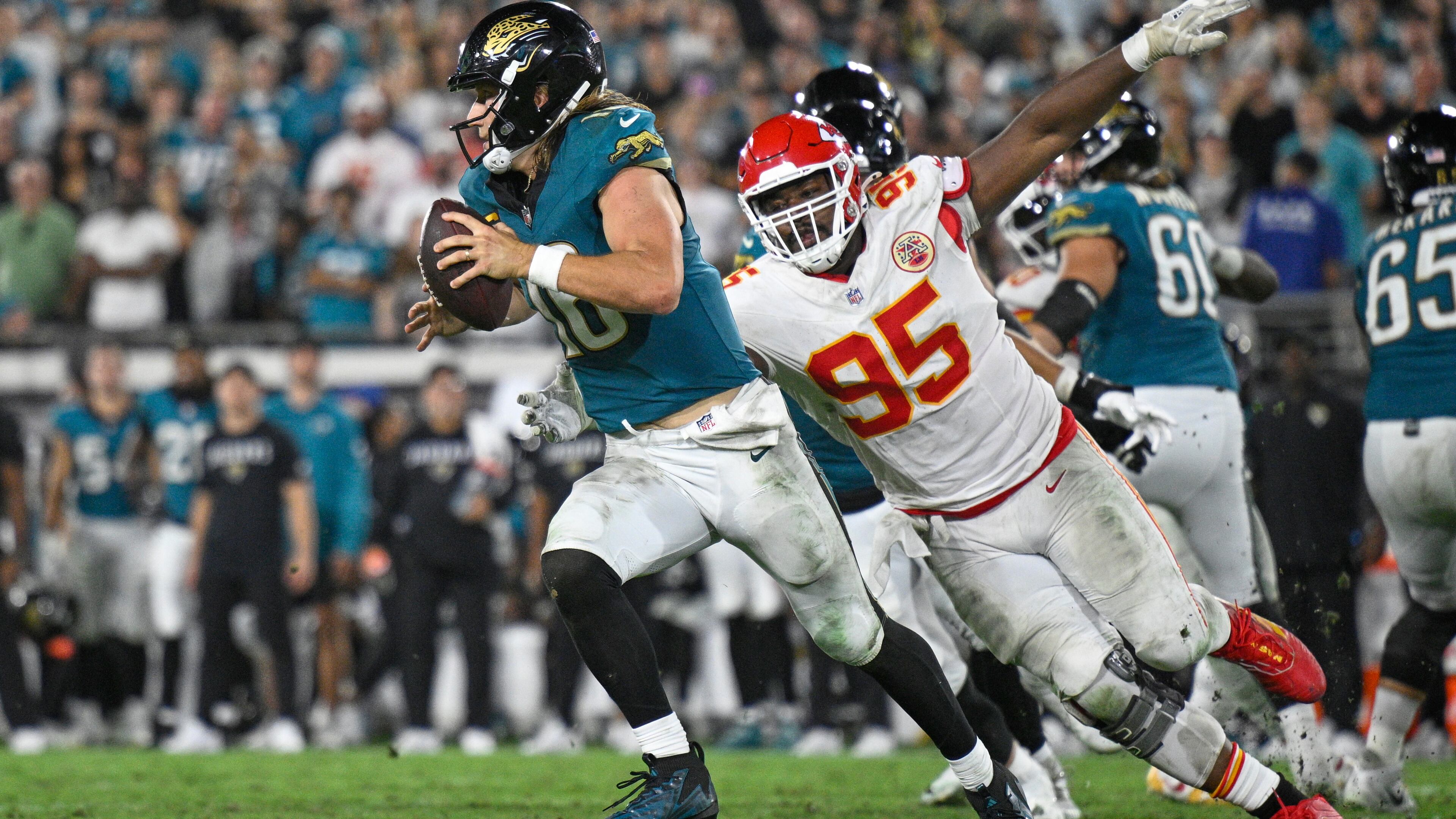 Jacksonville Jaguars quarterback Trevor Lawrence (16) gets past Kansas City Chiefs defensive tackle Chris Jones (95) as he runs the ball during the second half of an NFL football game, Monday, Oct. 6, 2025, in Jacksonville, Fla. (AP Photo/Phelan M. Ebenhack)