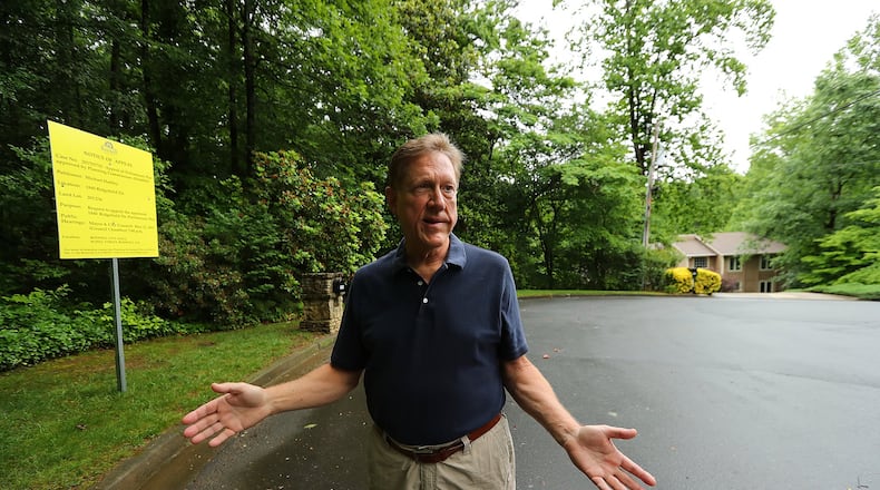 Michael Hartley stands beside the property his neighbor is trying to sell next door to his home on a cul-de-sac where a developer hopes to add around 20 new homes in Roswell. Curtis Compton/ccompton@ajc.com