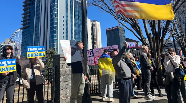 A protester holds up an American flag faded into a Ukrainian flag at Centennial Olympic Park.