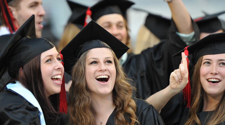 University of Georgia graduates Mackenzie Clark, Jennifer Lvovich and Kate Melton smile to friends and family in the stands during the procession of the Georgia 2014 Spring undergraduate commencement at Sanford Stadium in Athens on Friday night, May 9, 2014. HYOSUB SHIN / HSHIN@AJC.COM