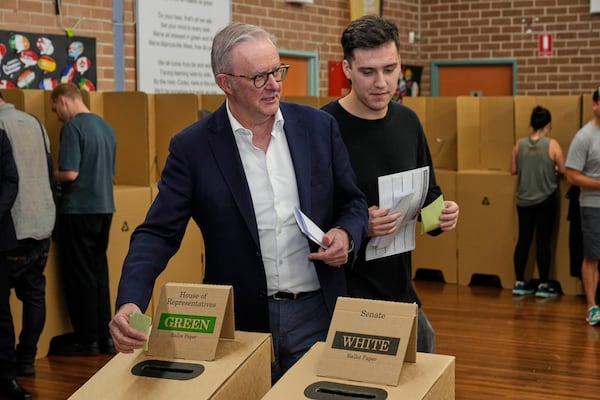 Australian Prime Minister Anthony Albanese and his son Nathan place their votes in a ballot box at a polling booth in his electorate in Sydney, Saturday, May 3, 2025. (AP Photo/Rick Rycroft)