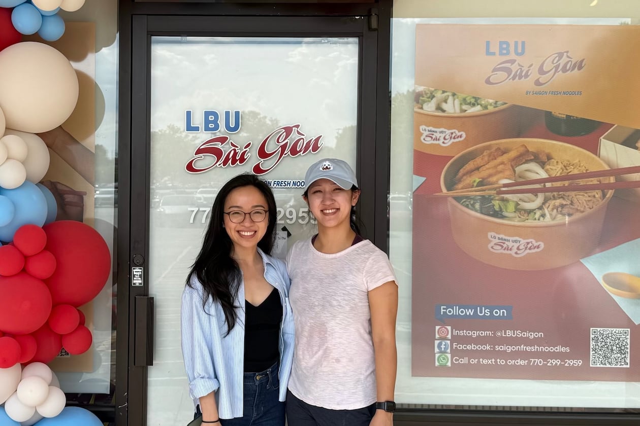 Two women, Trang Vu and her sister Trinh Vu, standing in in front of their noodle shop called LBU Saigon.