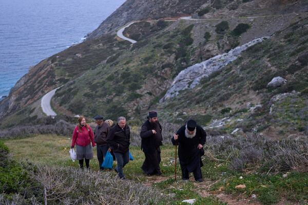 Orthodox Christian monk Father Spyridon of Amorgos, right, Father Antonis and other faithful leave the chapel of Panagia Evangelistria, after participating in Divine Liturgy in Amorgos island, Greece, on Monday, March 24, 2025. (AP Photo/Petros Giannakouris)