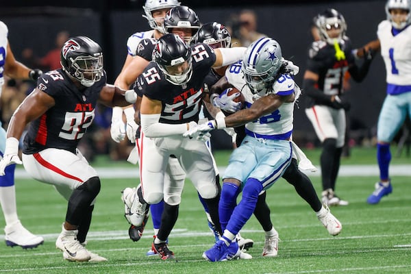 Atlanta Falcons linebacker Kaden Elliss (center) tackles Dallas Cowboys wide receiver CeeDee Lamb (right) during the first half of an NFL football game at Mercedes-Benz Stadium in Atlanta.  (Miguel Martinez/AJC 2024)