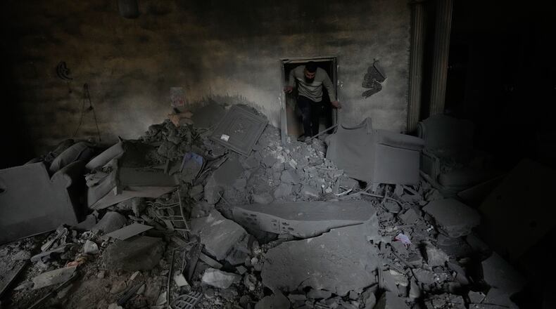 A man checks his damaged apartment at the site of a destroyed building that was hit in an Israeli airstrike in the southern port city of Tyre, Lebanon, Thursday, March 26, 2026. (AP Photo/Hussein Malla)